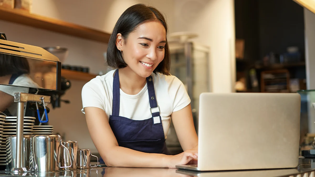 Cafe business owner on laptop in store
